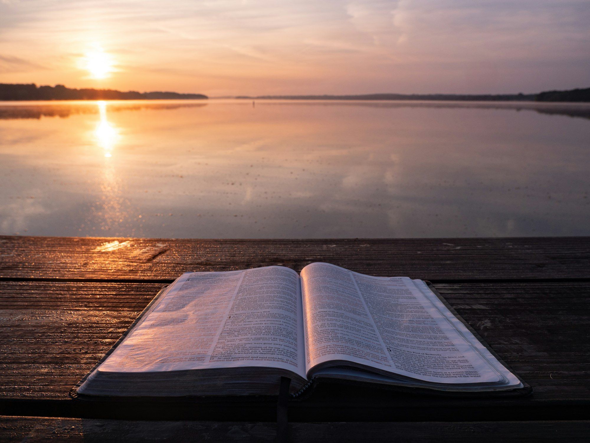 Biblia abierta junto al agua al atardecer